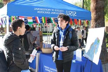 An international student talking to one of the International Gateways instructors on a Global Spartan tabling event.